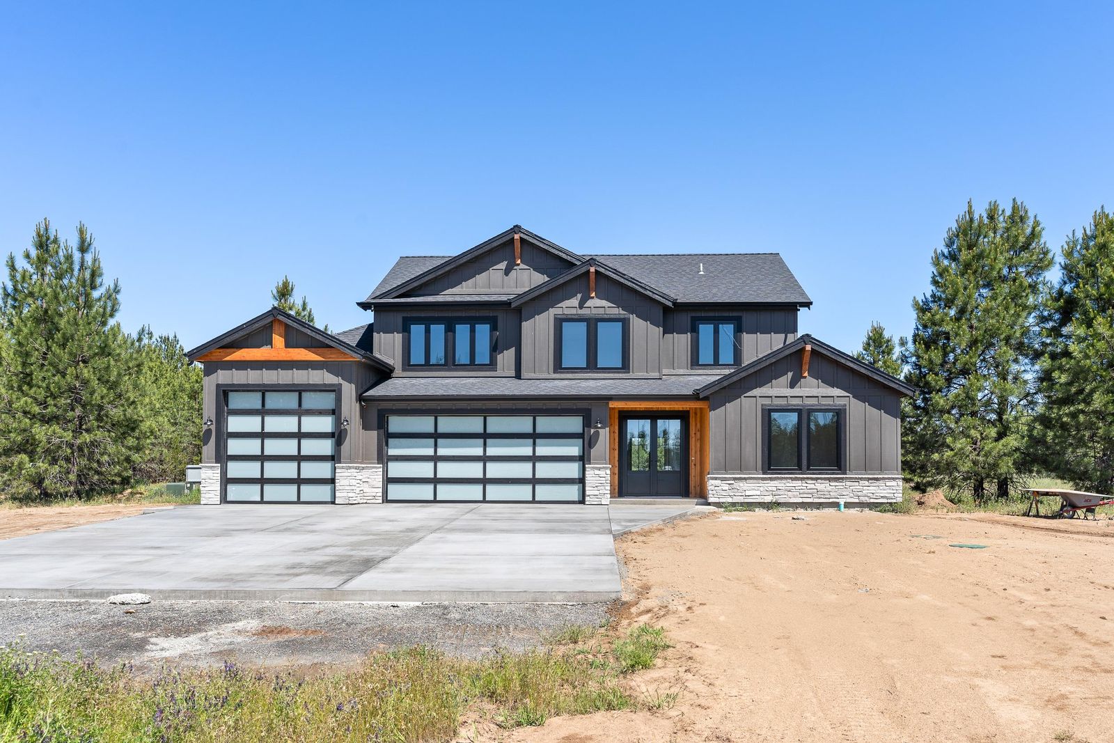 Dark bronze two-story with glass garage doors and stone accents from the same build package
