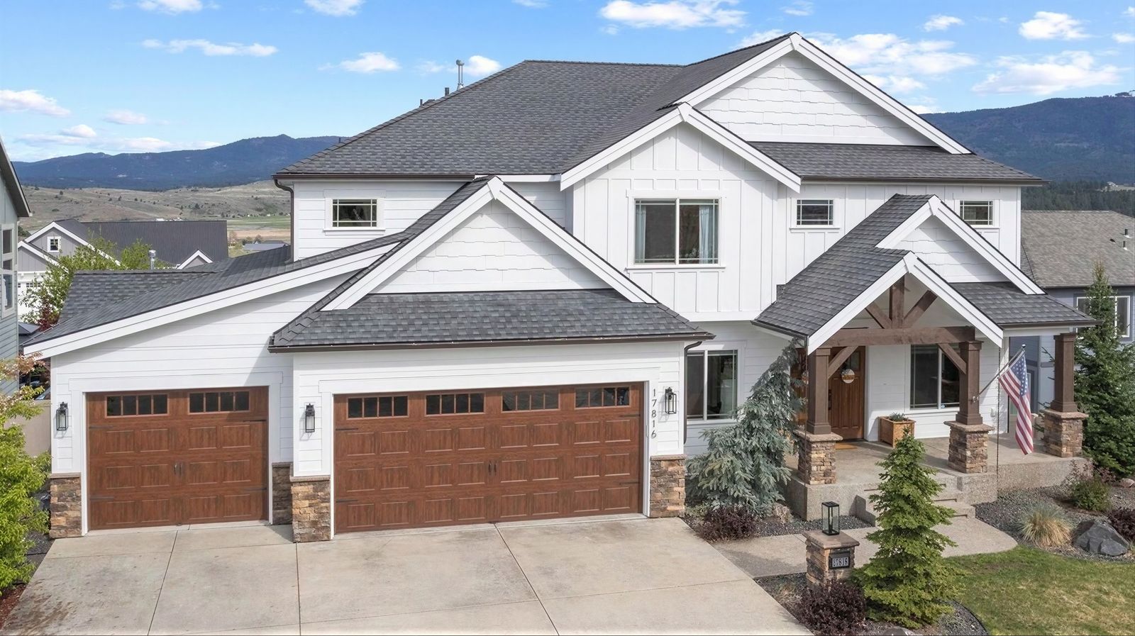 White two-story home with cedar-tone garage doors in Liberty Lake